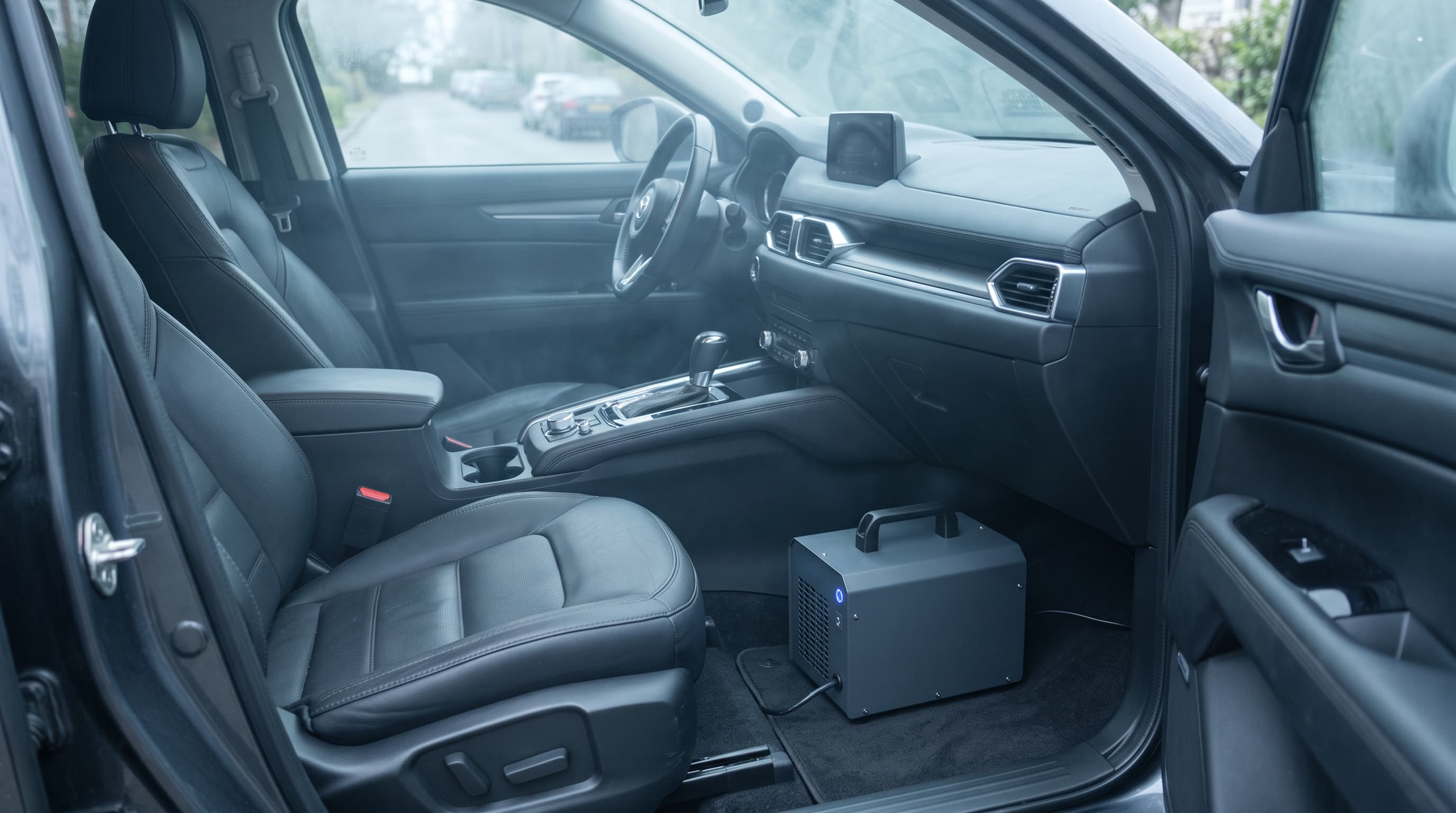 Ozongerät im Fußraum eines Fahrzeugs mit dunklen Ledersitzen und geöffneten Türen