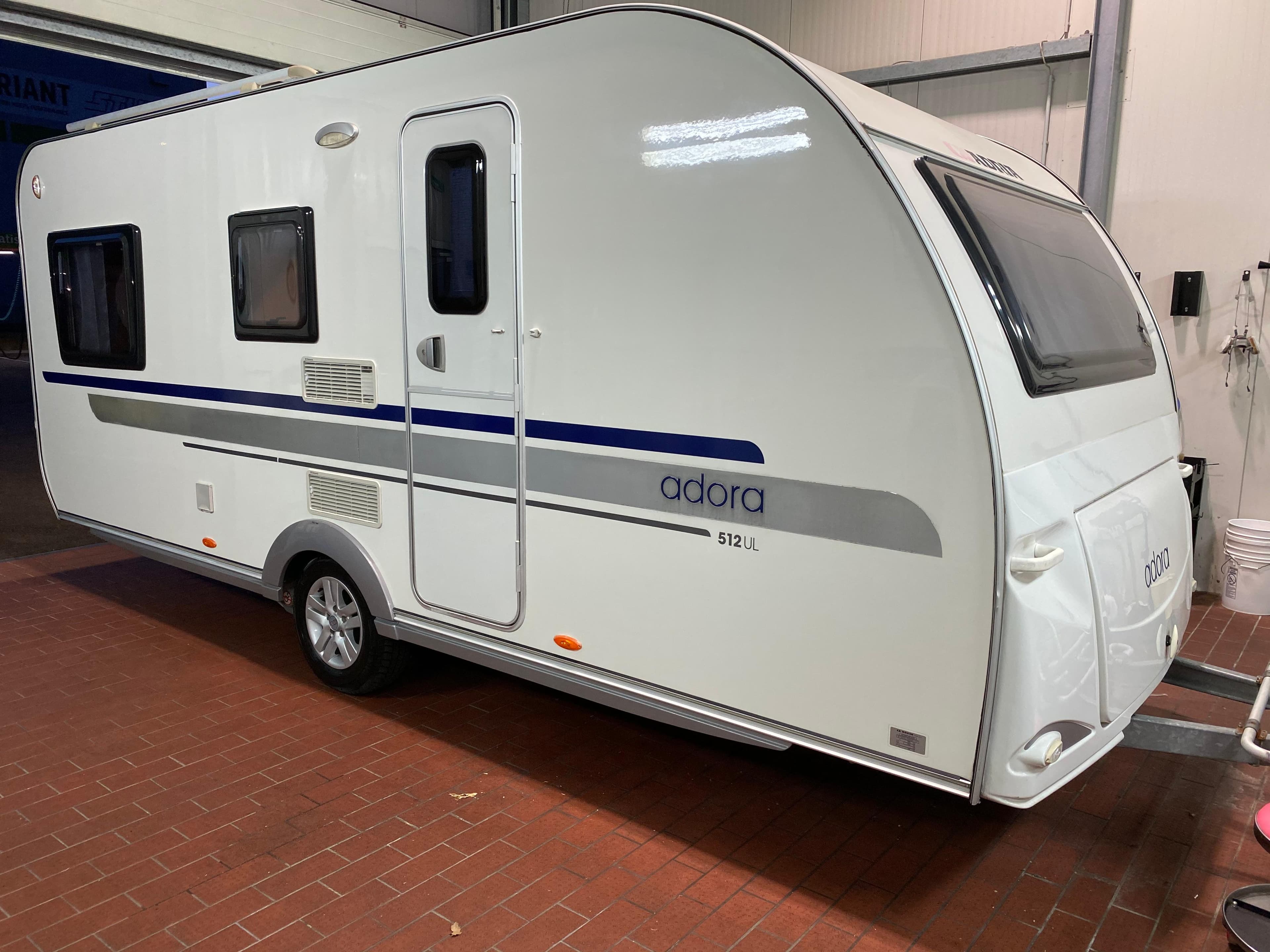 Wohnwagen Adria Adora 512 UL in einer Halle mit rotem Fliesenboden